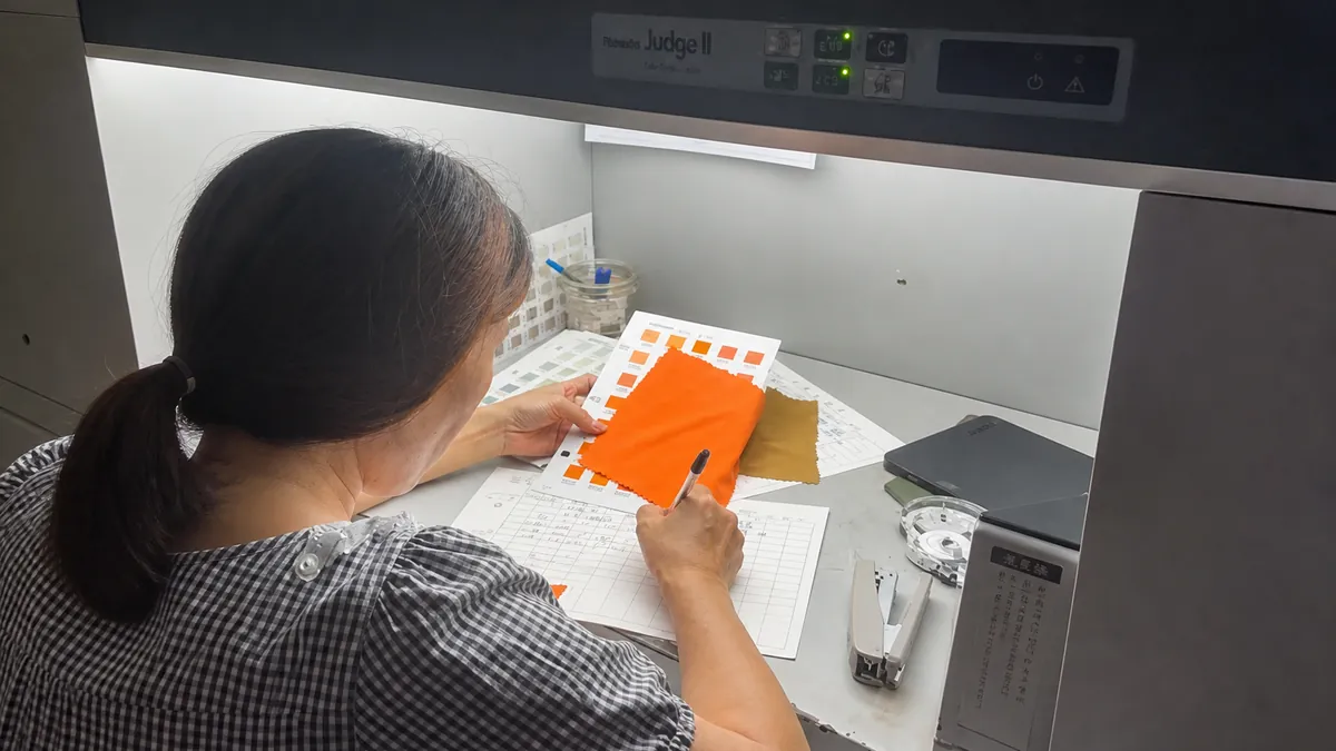 Colorist matching dyed fabric against a color standard
