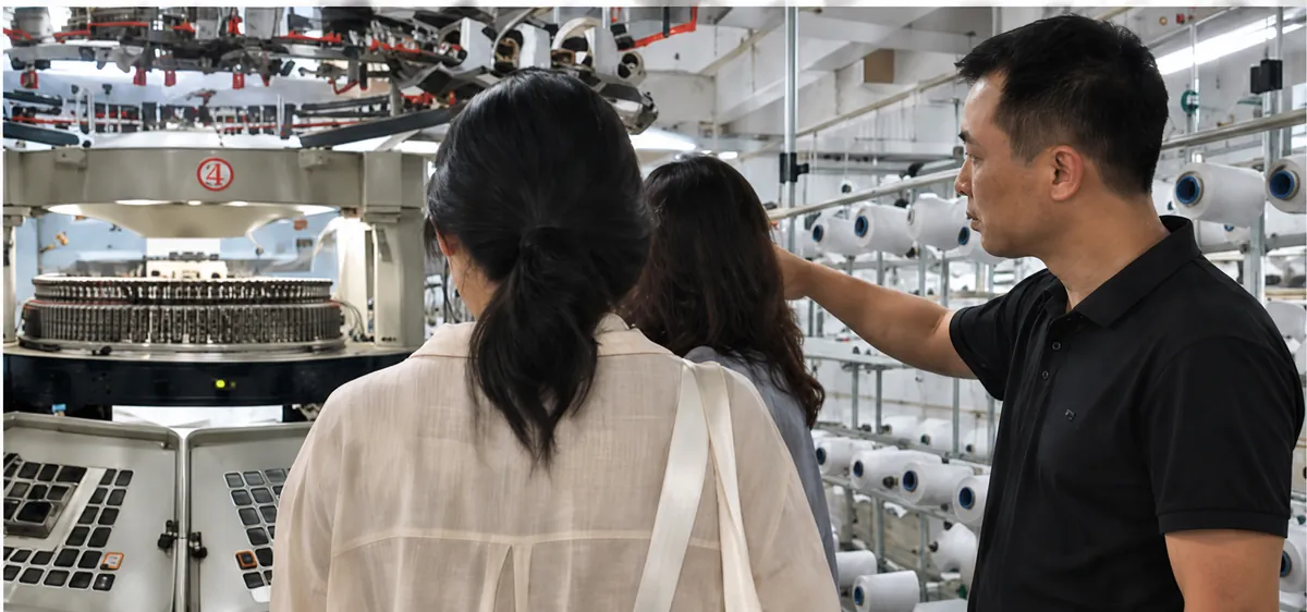 Factory staff explaining knitting equipment to visiting buyers
